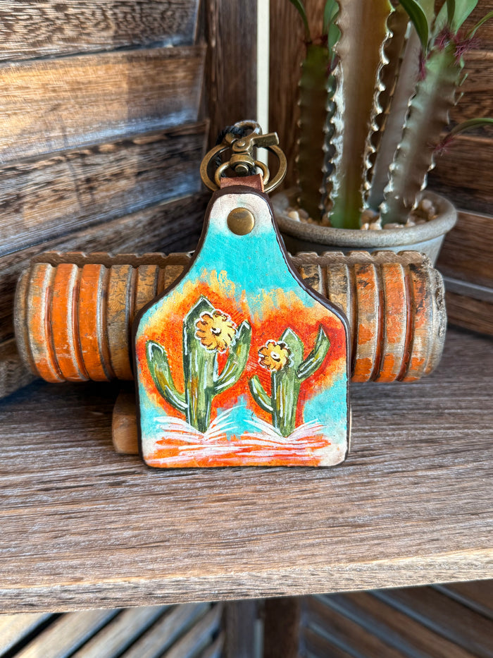 Turquoise painted cactus leather keychain with two cartoon cacti and brass keyring