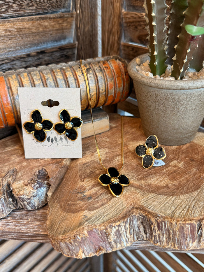 Black floral stud earrings with gold-tone petal frame on paper card