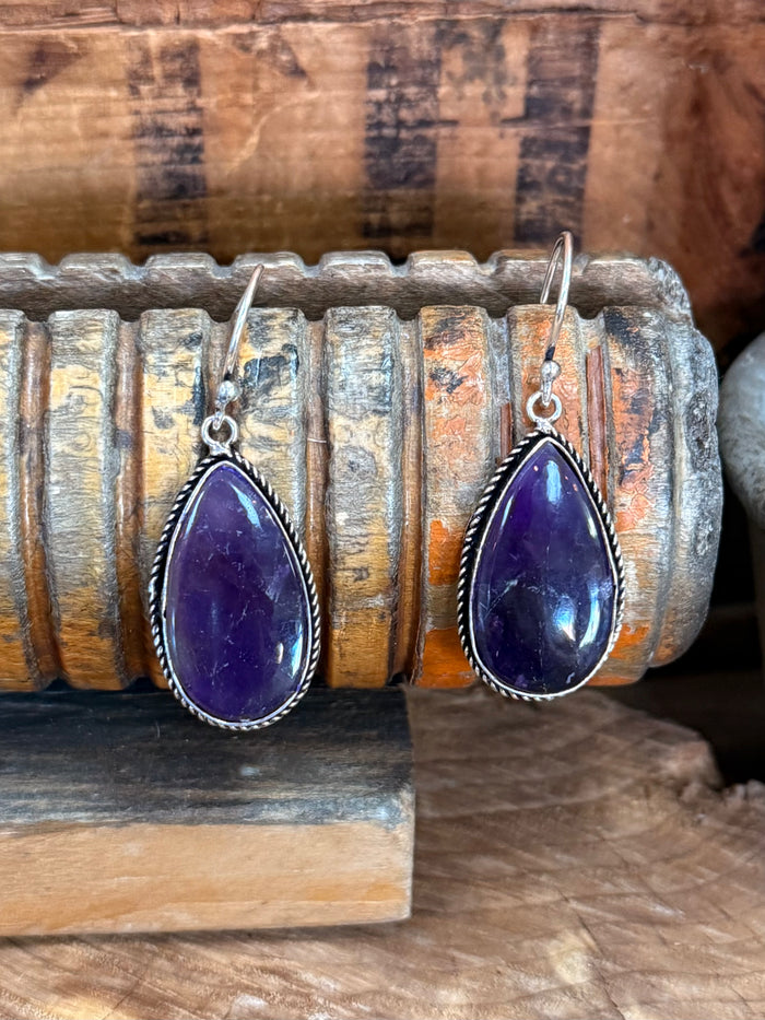 Silver fishhook earrings with purple teardrop amethyst stones and ornate border