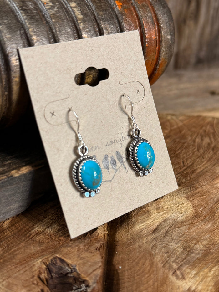 Turquoise oval fishhook earrings with silver beaded frames, side view
