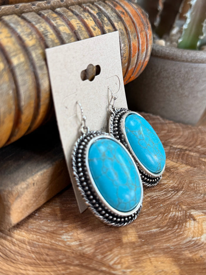 Silver fishhook earrings with two oval turquoise stones, textured beaded border