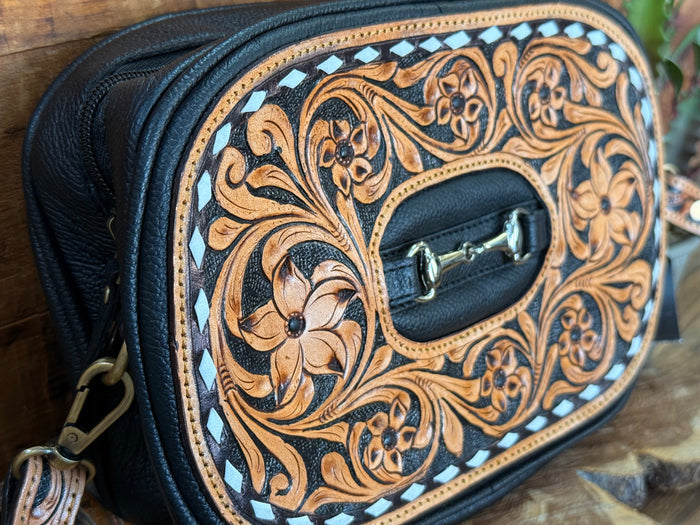 Tooled crossbody purse detail: oval flap with engraved floral leather and silver buckle