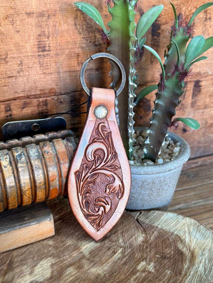 Teardrop cowhide key fob with carved floral design, copper-brown tooling, metal ring