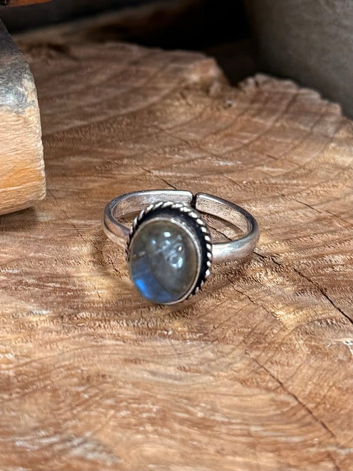 Silver-plated ring featuring a blue teardrop stone with beaded bezel and open band