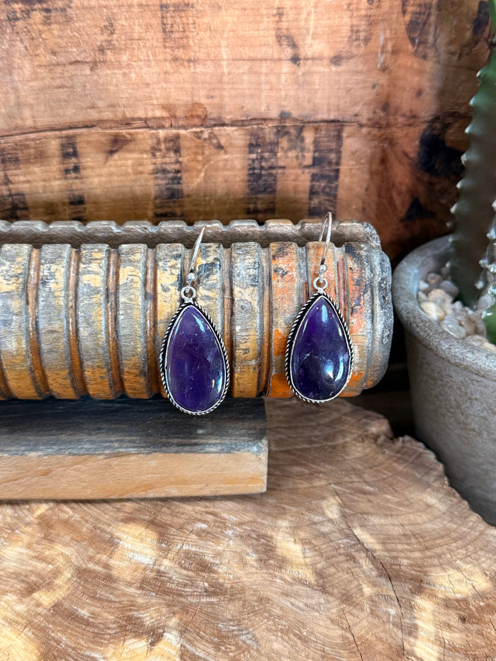 Silver fishhook earrings with purple teardrop amethyst stones and faceted setting