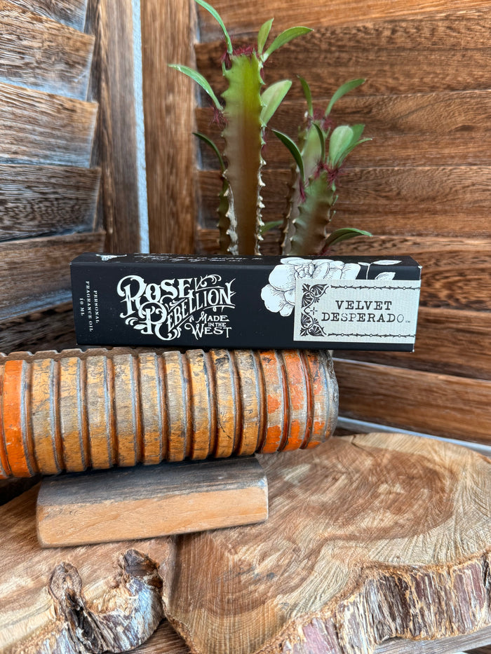 Velvet Desperado roll-on perfume oil in black and white label box, on rustic wood