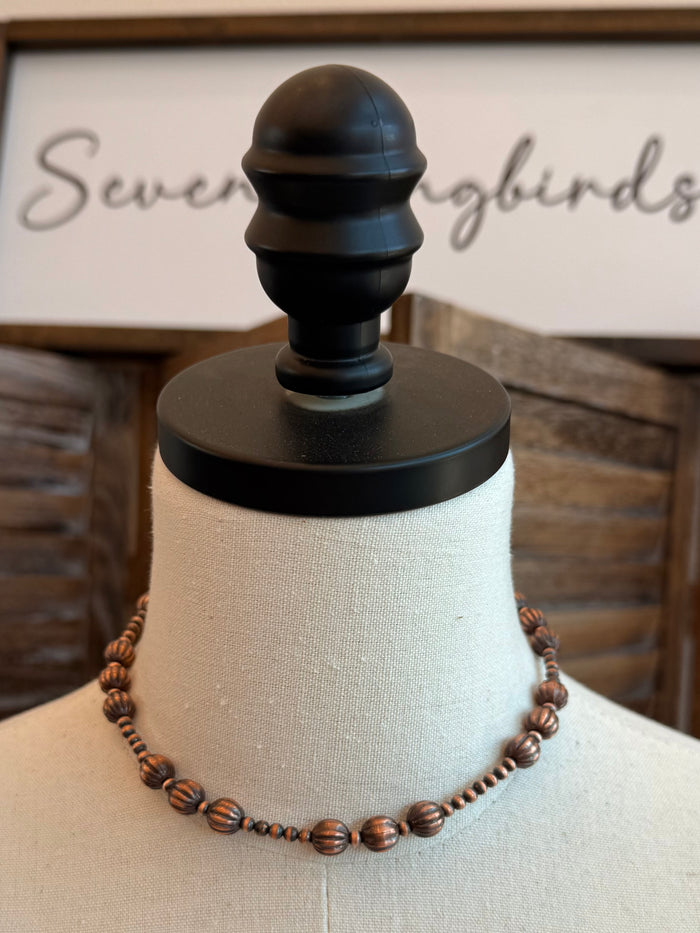 Copper pumpkin-bead necklace on display bust, short beaded chain