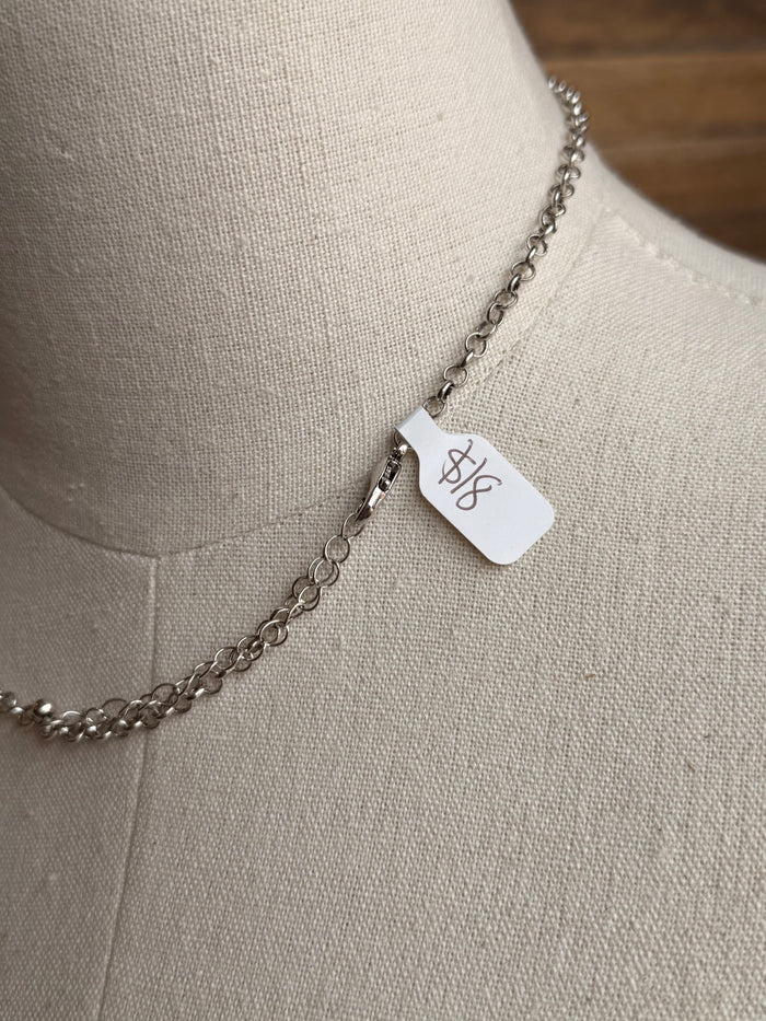 Turquoise bar necklace with silver chain and small white brand tag