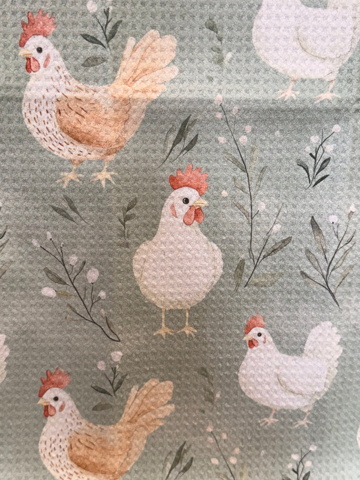 Light sage towel close-up with white hens, orange roosters, and branch details