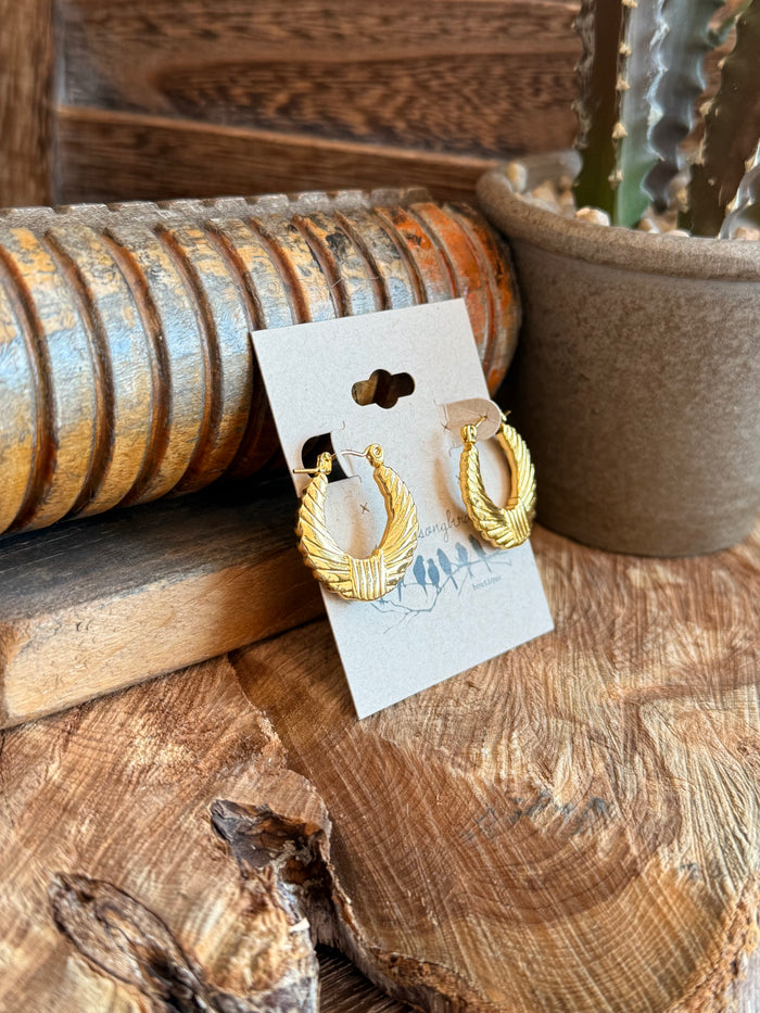 Gold-tone half hoop earrings with ribbed texture and small charm, pair on card
