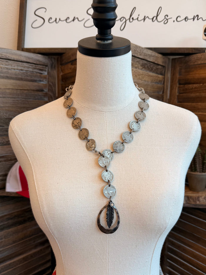 Feather pendant necklace with mixed coin charms and oval drop centerpiece