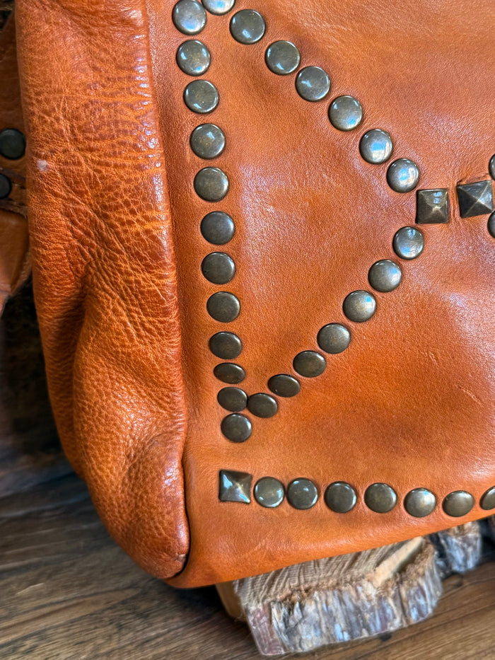 Studded cognac leather flap corner with round studs and metal rivet trim