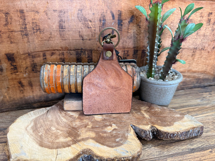 Leather key fob with round metal keyring and tan-brown painted-free surface