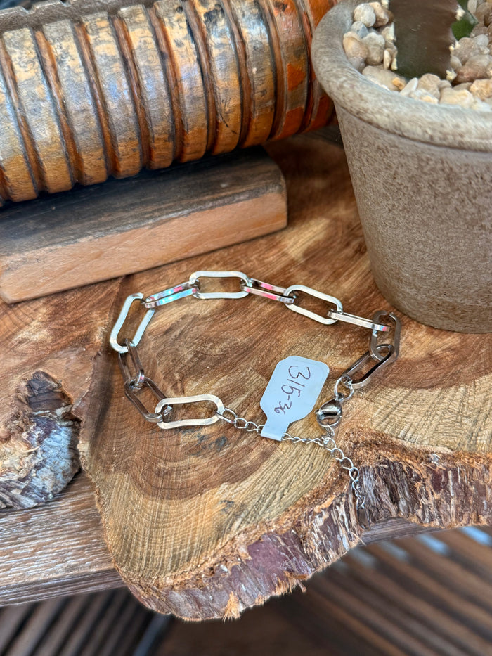 Silver clasp bracelet with oval links, small multicolor stones, and charm tag