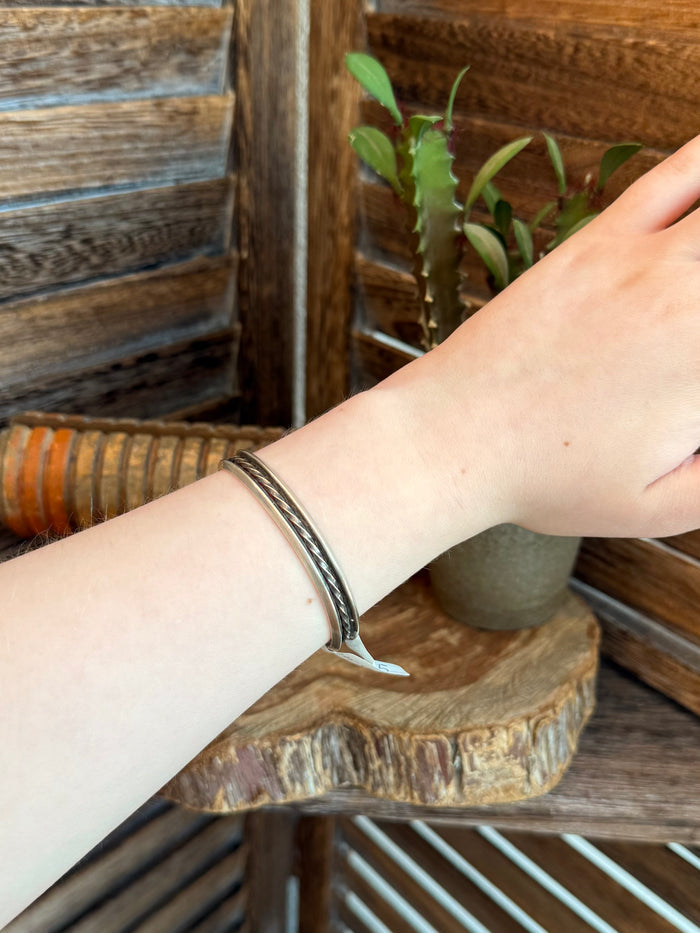 Silver cuff bracelet on wrist, turquoise inlay detail along the band