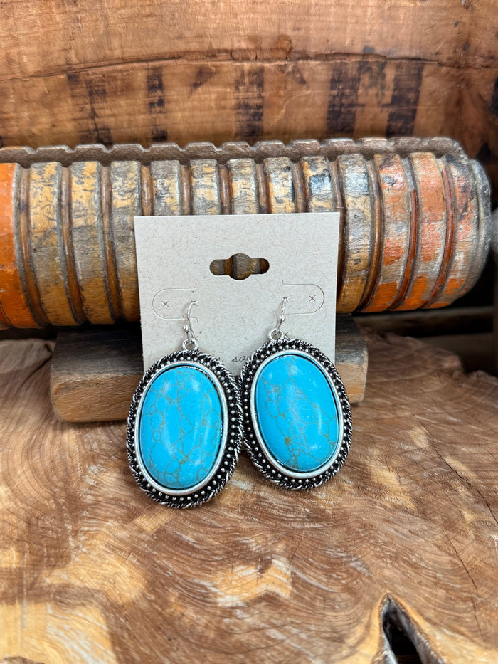 Silver fishhook earrings with large oval turquoise stones, beaded halo setting