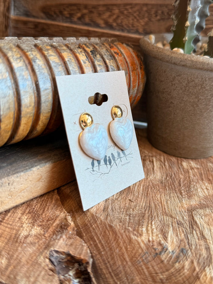 Light blue heart stud earrings with gold-tone posts, angled view on card.