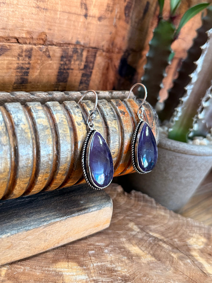 Pair of silver fishhook amethyst earrings with purple teardrop stones and openwork frame