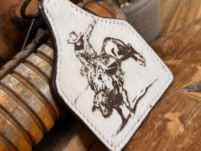 Hair-on key fob close-up of white patch with bull rider and horse artwork
