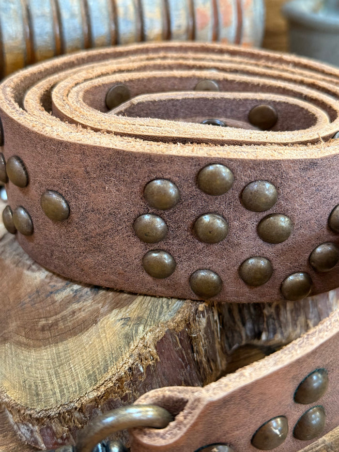 Brown leather strap close-up with round brass studs and double stitched edges