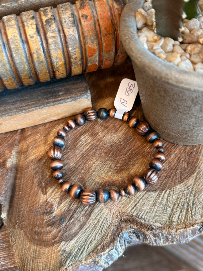 Copper bead stretch bracelet with blue spacers and white hang tag