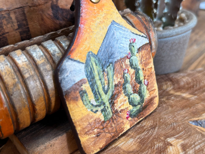 Handpainted cactus leather key fob close-up with blue desert and green cactus illustration