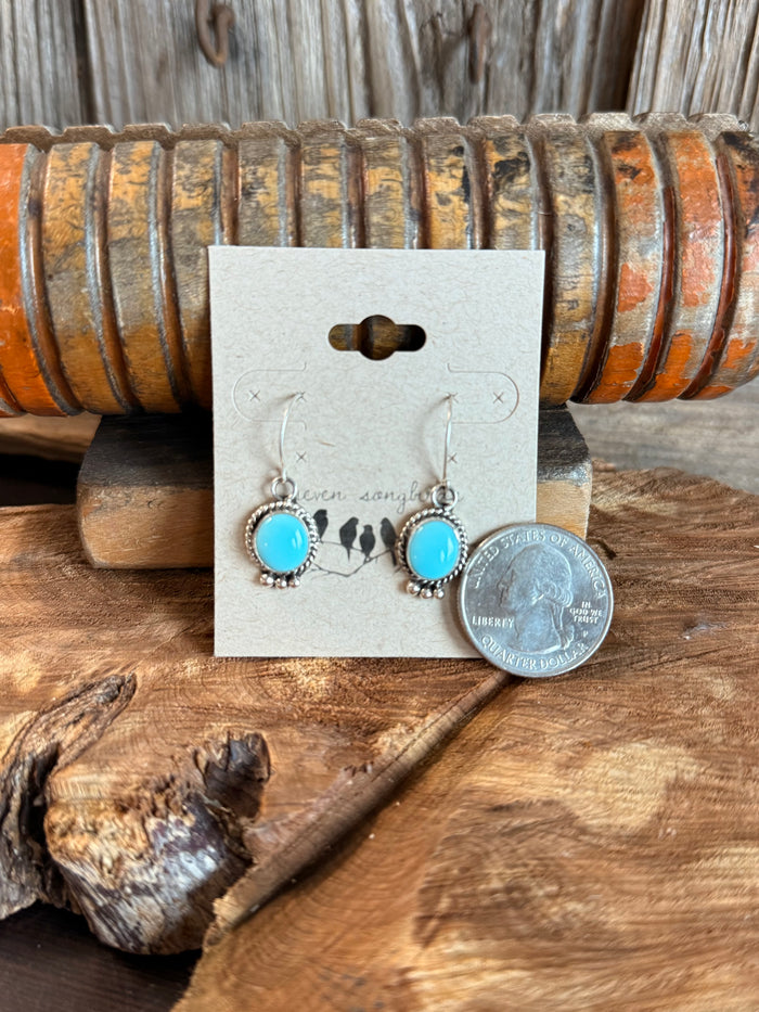 Turquoise round fishhook earrings with ornate silver frames, shown with coin size