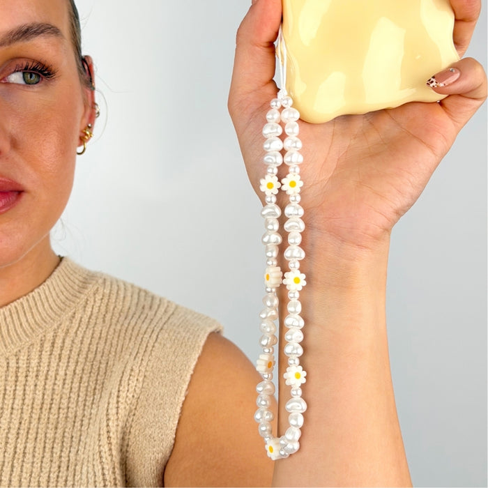 Daisy pearl phone strap being held up by model