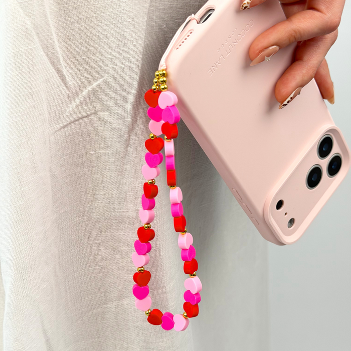 close up of hearts phone strap attached to butter soft pink phone case