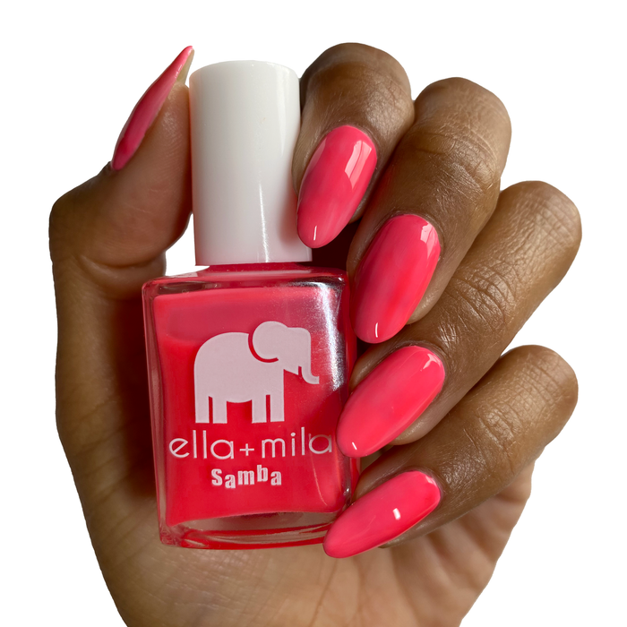 Bellini coral hot pink nail polish on a deep skin tone, hand holding the bottle