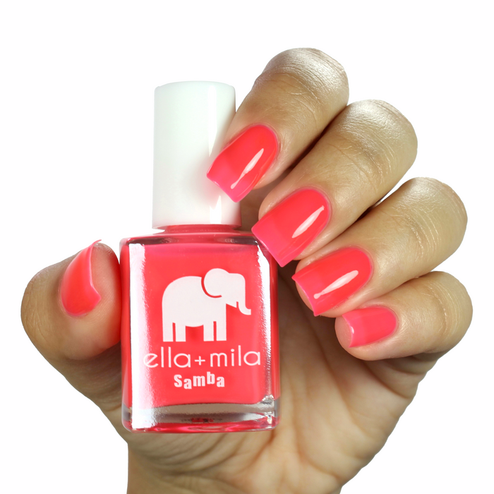 Bellini bright coral pink nail polish on a medium skin tone, hand holding the bottle