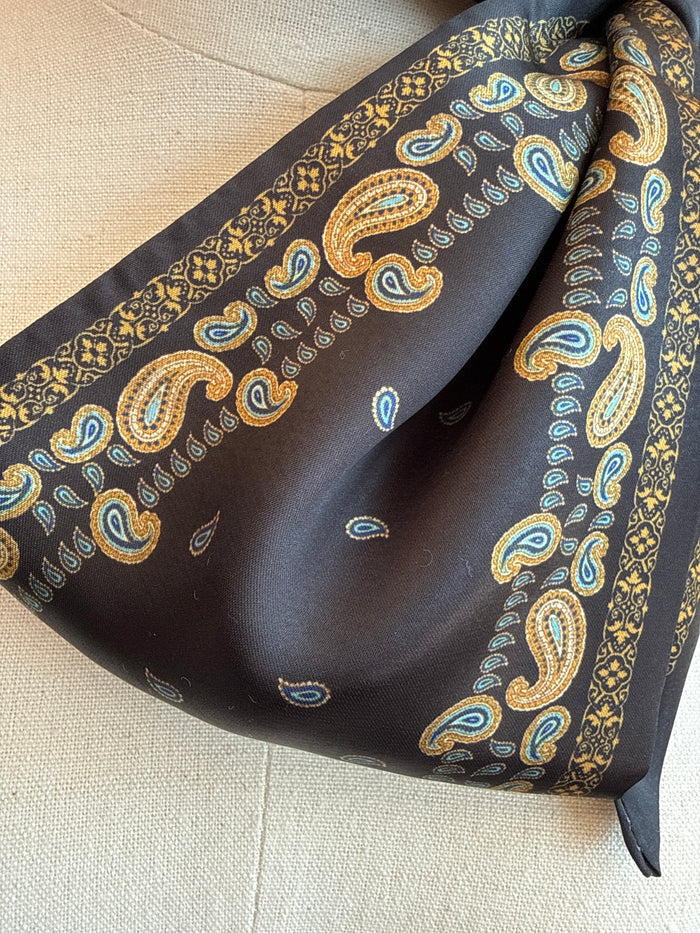 Black paisley twilly scarf with gold and blue paisley pattern, folded close-up