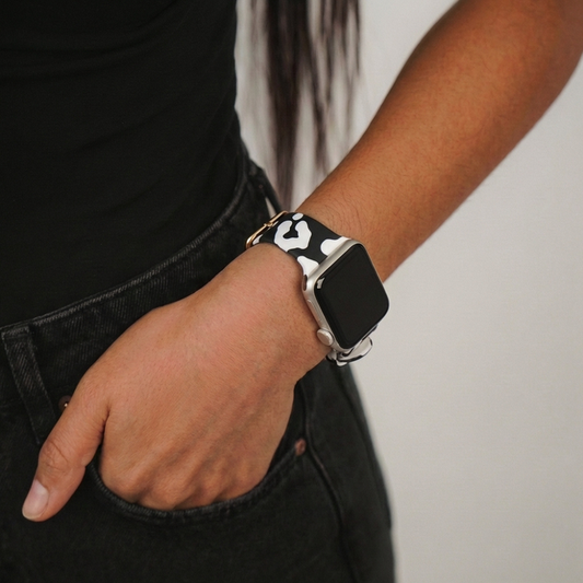 Coconut Lane Black Leopard Apple Watch strap on models wrist, hand in pocket, plain light background.