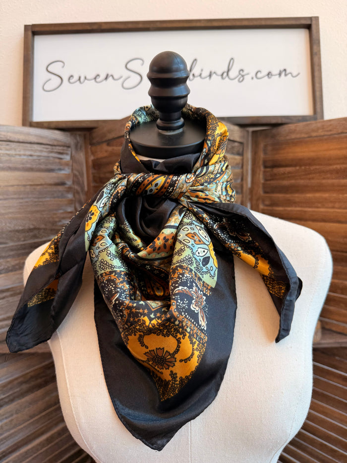 Wild rag scarf knotted on mannequin hat, black with gold and colorful paisley print