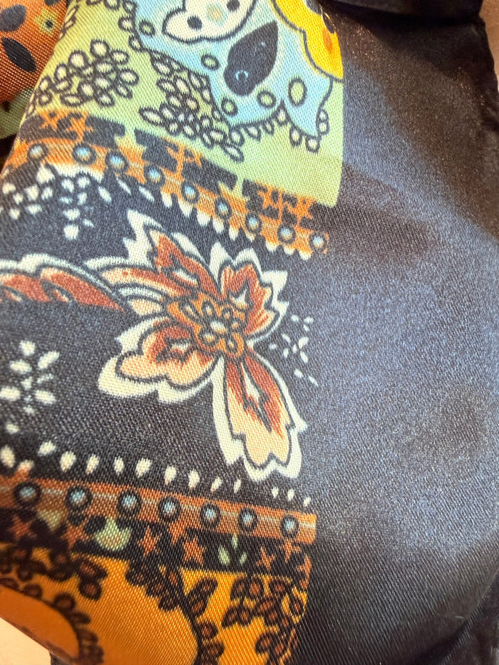 Wild rag scarf close-up of paisley floral pattern in gold, orange, teal on dark fabric
