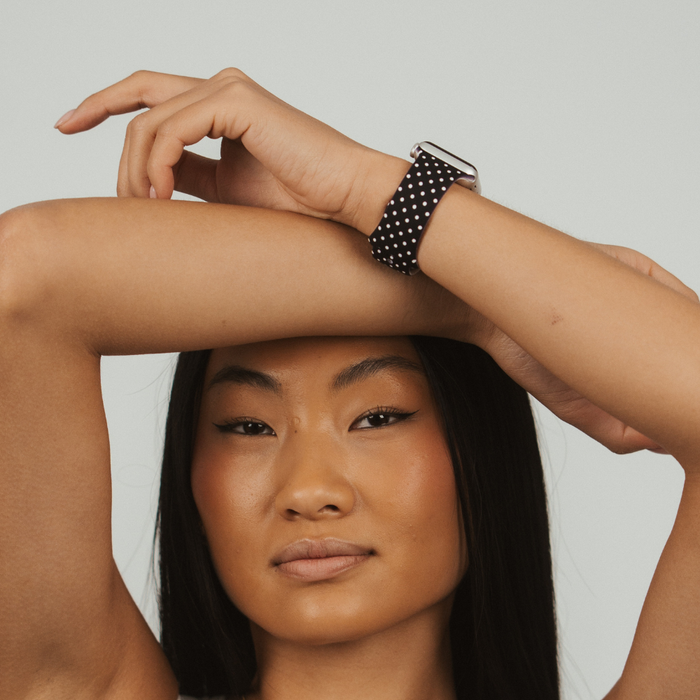 Woman wearing a black Apple Watch strap with white polka dots from Coconut Lane.
