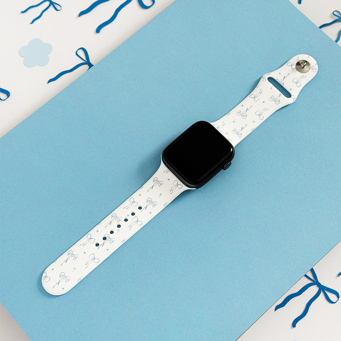White silicone Apple Watch strap with blue bow pattern by Coconut Lane.