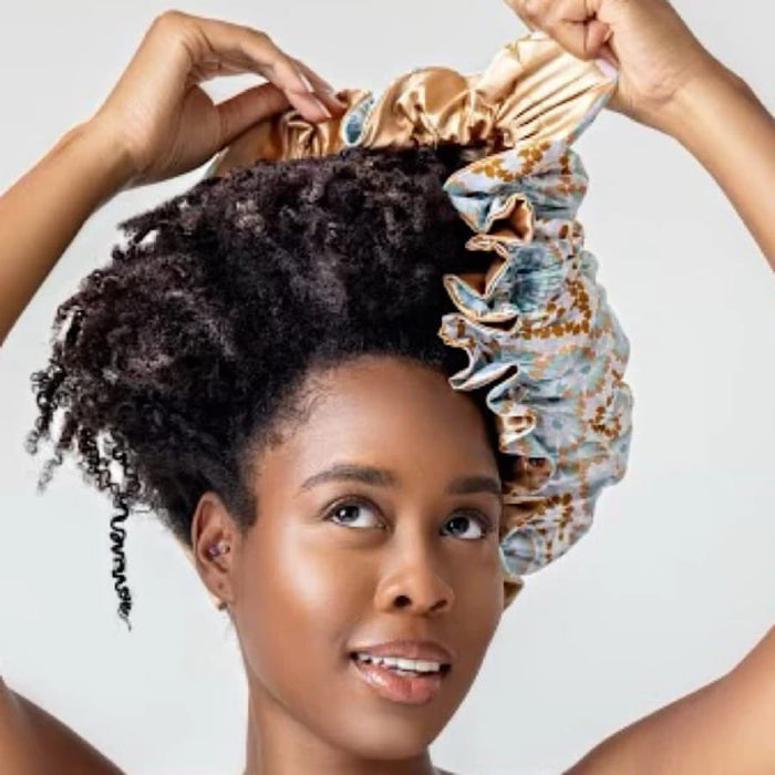 Woman with curly hair adjusting patterned satin bonnet for nighttime hair care