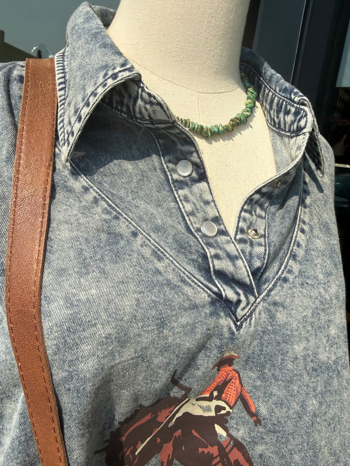 Light blue denim graphic shirt with button placket and partial front horse print