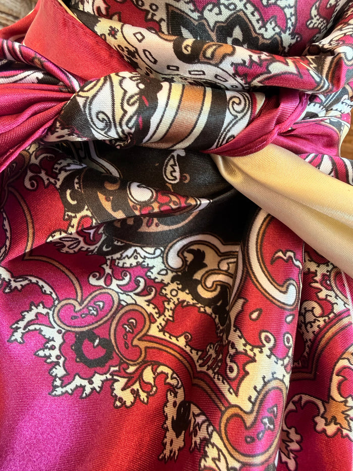 Paisley wild rag scarf tied in a knot, showing maroon, pink, and cream patterns