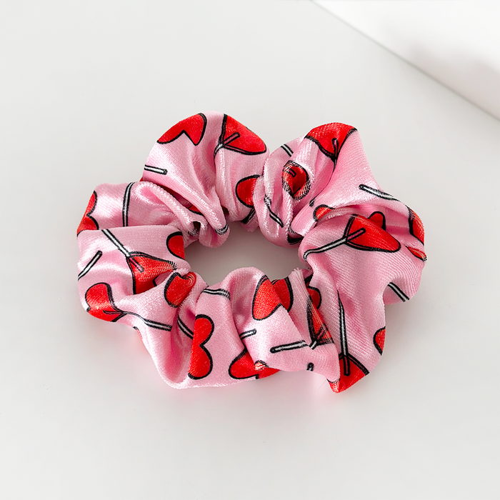 Pink satin scrunchie with a pattern of red heart-shaped sunglasses.