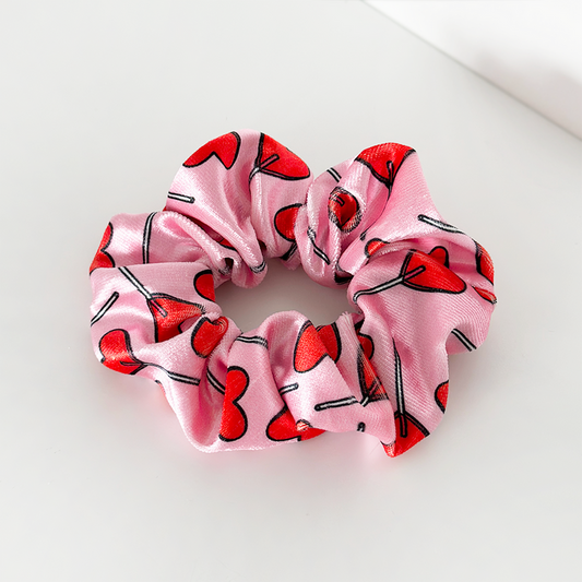 Pink satin scrunchie with a pattern of red heart-shaped sunglasses.