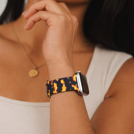 Woman wearing a sleeveless top and gold necklace with a tortoiseshell Apple Watch strap.
