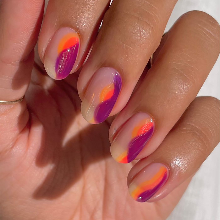 Chicha purple and orange abstract French tip nail art on a light skin tone