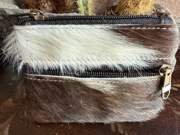 Brown and white cowhide coin purse with two black zippers and metal pulls