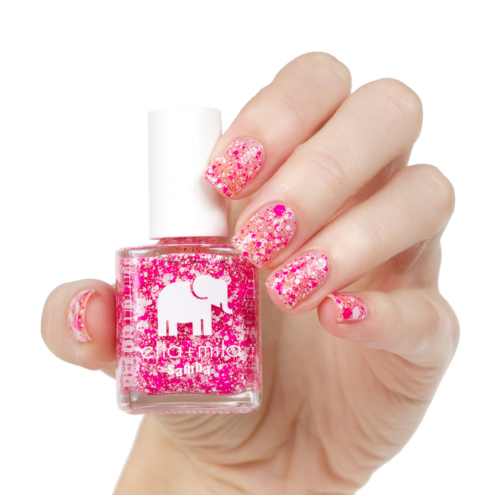 Congo Bongo pink confetti glitter nail polish on a light skin tone, hand holding the bottle