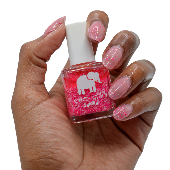 Congo Bongo pink confetti glitter nail polish on a deep skin tone, hand holding the bottle