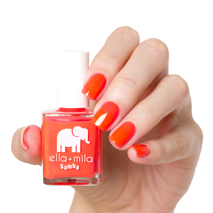 Coral Crush orange coral nail polish manicure on a light skin tone with the bottle