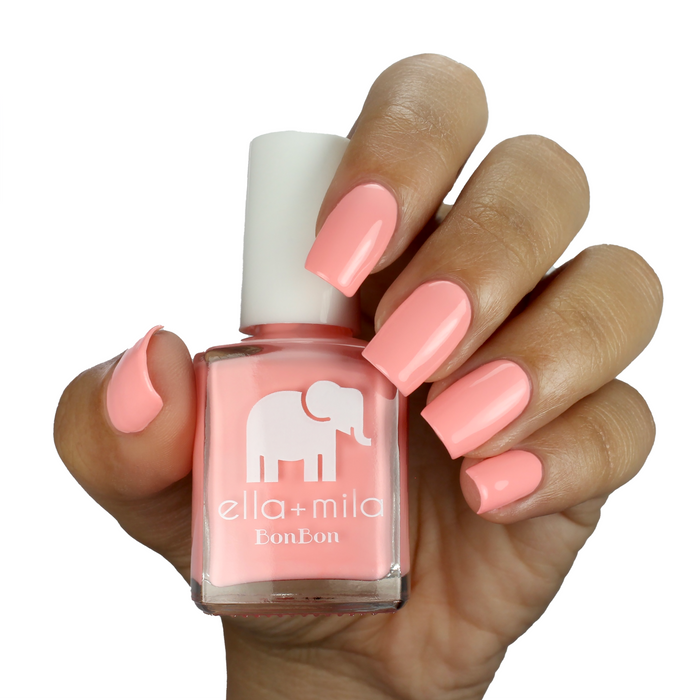 Creamsicle creamy peach nail polish on a medium skin tone, hand holding the bottle
