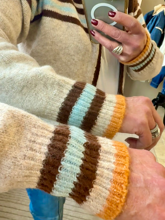Tan cardigan sleeve with brown, light-blue, and orange striped knit cuff